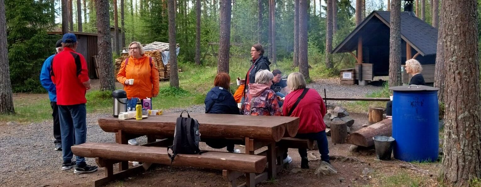 Kuvassa ihmisiä metsässä grillamassa